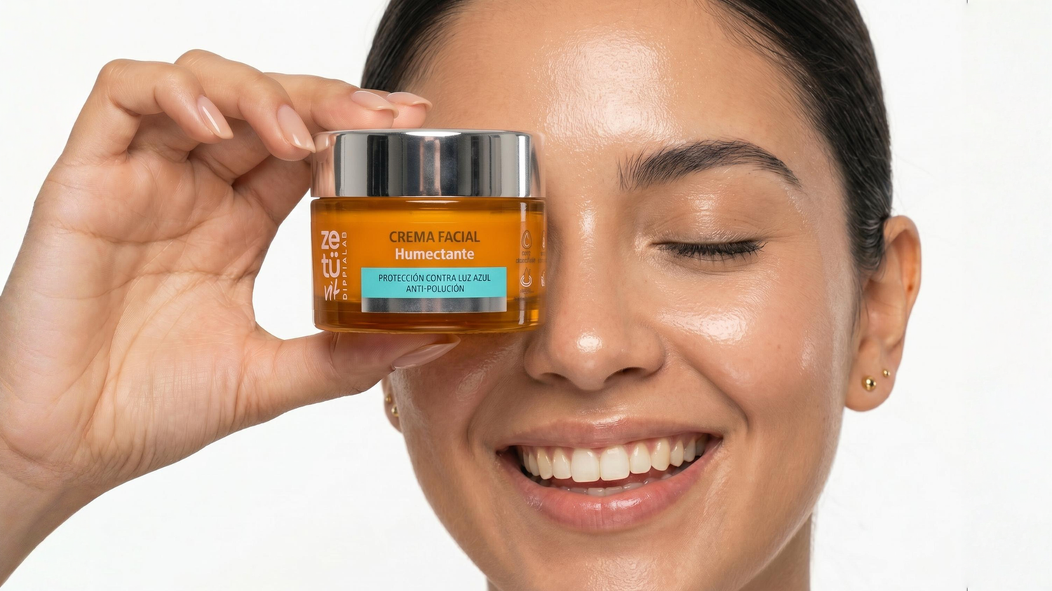 Mujer sosteniendo un frasco de la Crema facial humectante frente a su cara